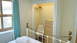 A bedroom with a bed, a wardrobe, a hanging chair, and a window with curtains. - Elder Cottage - UK51371 (Caldwell, Richmond)