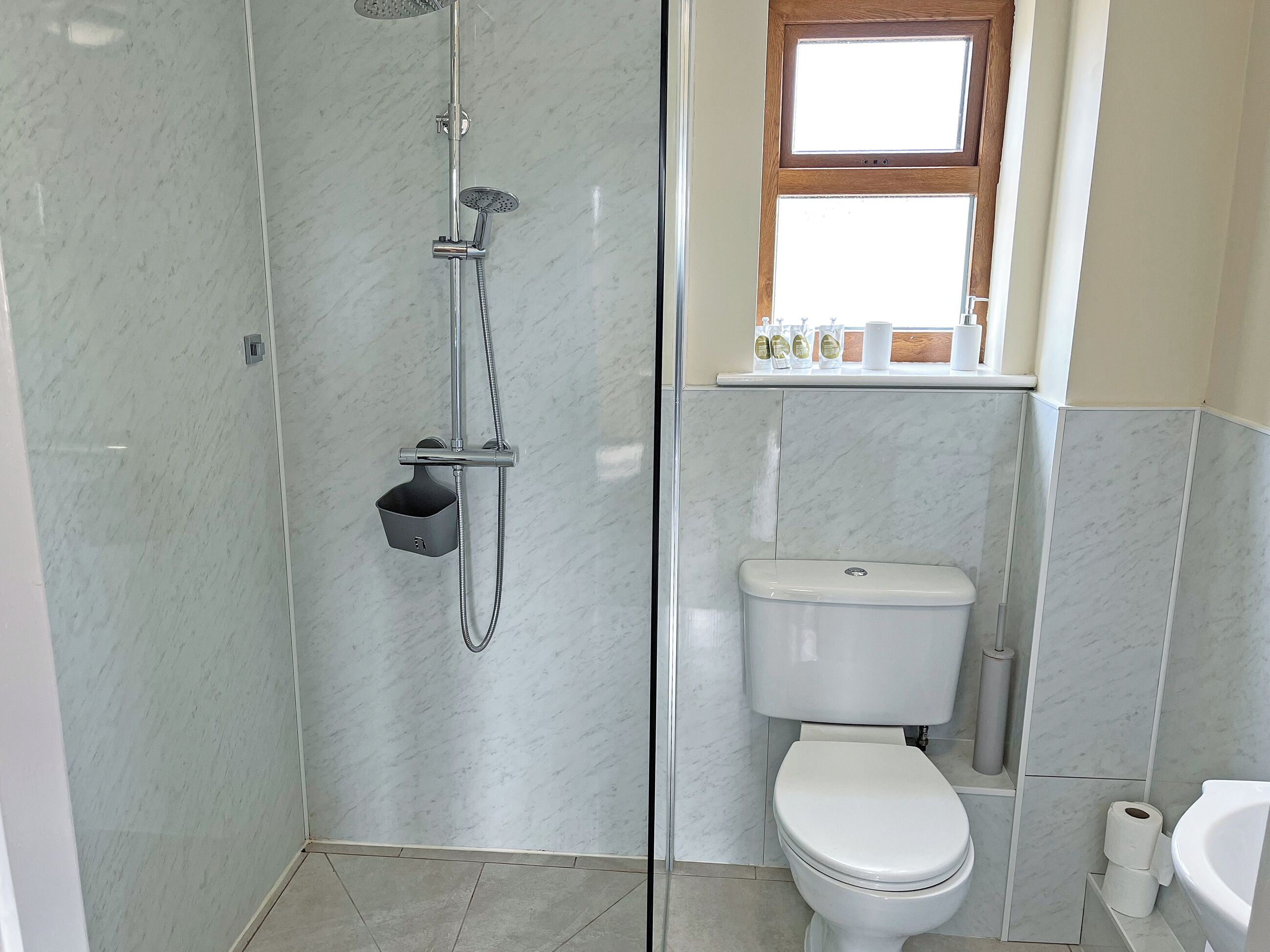 Une salle de bain avec une douche, des toilettes et une fenêtre.