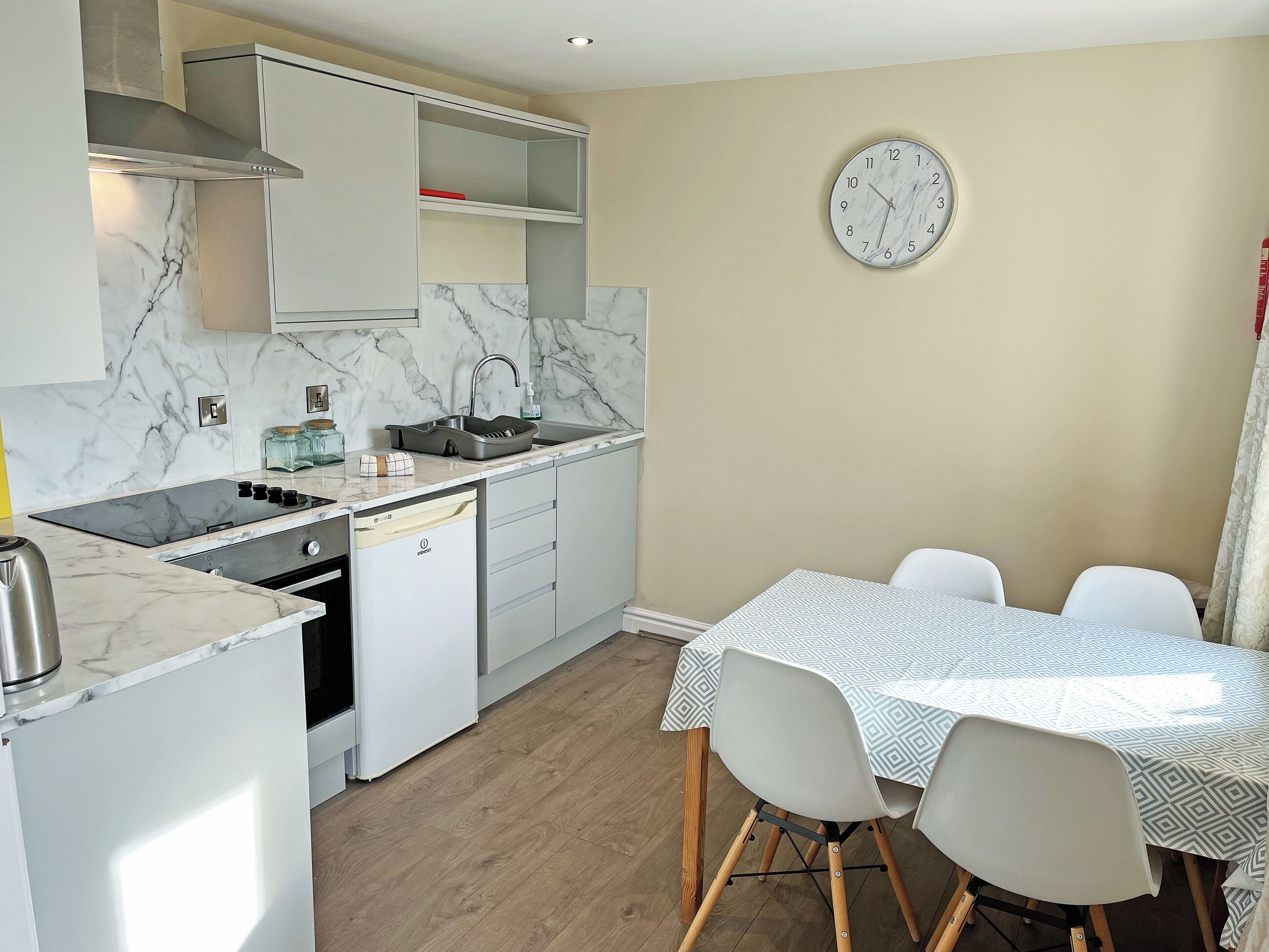 A modern kitchen with a built-in stove, dishwasher, and a dining area with a table and chairs.