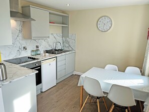 Une cuisine moderne équipée d’une cuisinière intégrée, d’un lave-vaisselle et d’un coin repas avec une table et des chaises.