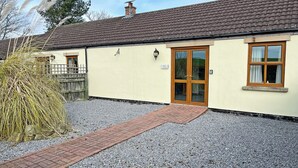 A building with a tiled roof, a wooden door, and a gravel driveway. - Elder Cottage - UK51371 (Caldwell, Richmond)