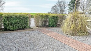 A gravel pathway leading through a hedge-lined area with a brick path, surrounded by various shrubs and trees. - Elder Cottage - UK51371 (Caldwell, Richmond)