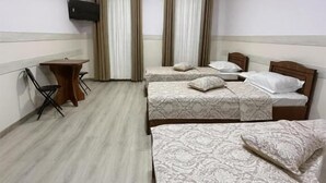 Una habitación de hotel con dos camas, un escritorio, una silla y un televisor montado en la pared.
