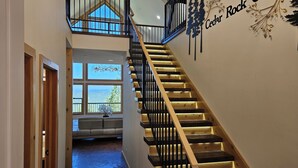 Eine Treppe mit Holzdielen und schwarzen Geländern führt zu einer zweiten Etage. Ein Schild an der Wand zeigt 