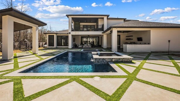 A modern two-story house with a swimming pool, covered patio, and a well-maintained lawn.