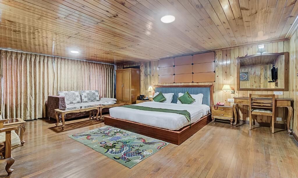 Une chambre à coucher aux murs lambrés, avec un lit, un canapé, un bureau et un miroir.