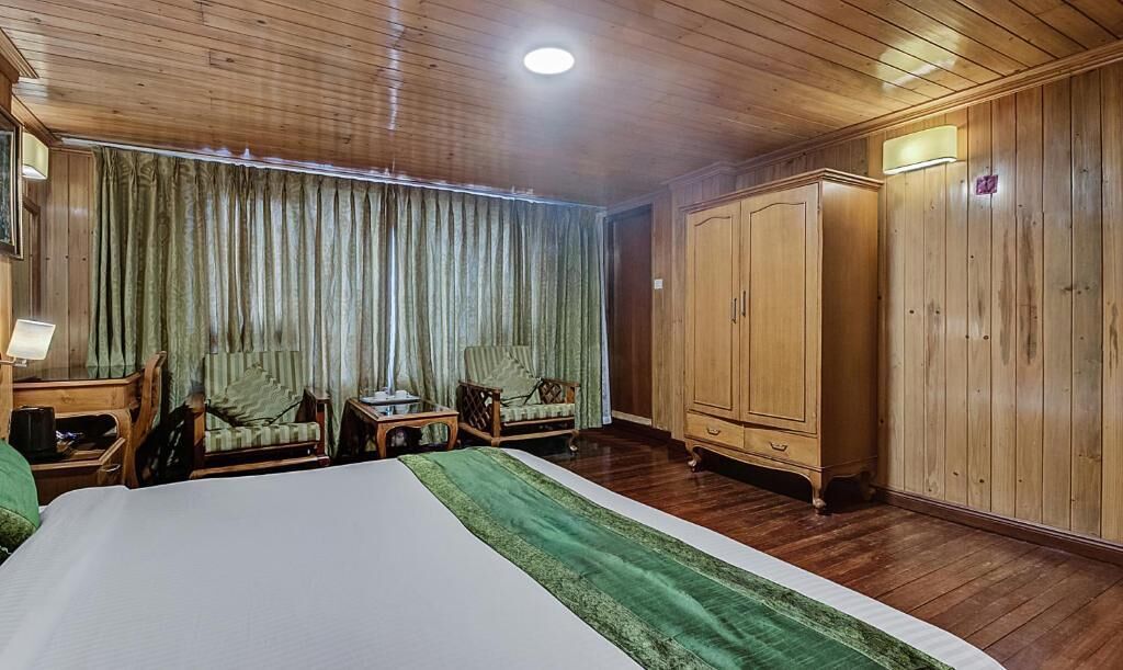 Ein Hotelzimmer mit einem großen Bett, einem Holzschrank, zwei Sesseln, einem kleinen Tisch und einer Lampe.