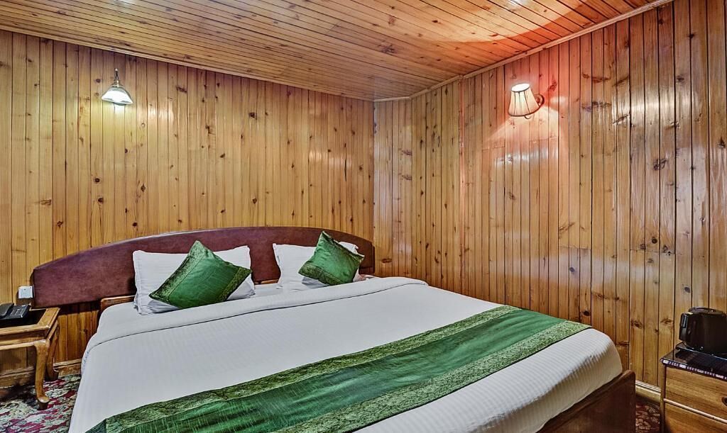A wooden-paneled room with a bed, nightstands, and a lamp.