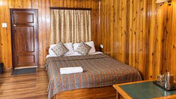 A wooden-paneled room with a bed, a bedside table, and a door.