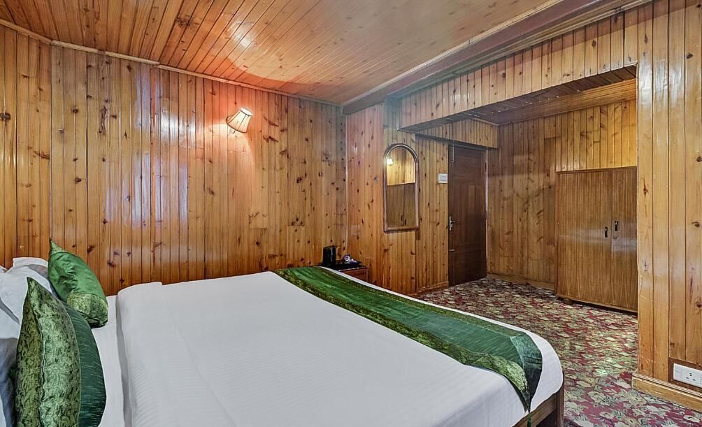 A wooden-paneled room with a bed, a mirror, a wardrobe, and a carpeted floor.