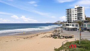 A beachside view with a modern building, a sandy beach, and the ocean. - MetaWise BNB Modern Studio in Central Cronulla 2 (Cronulla)