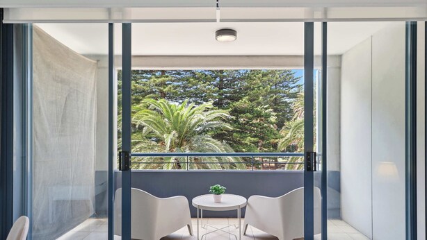 A balcony with two chairs, a small table, and a potted plant. - MetaWise BNB Modern Studio in Central Cronulla 2 (Cronulla)
