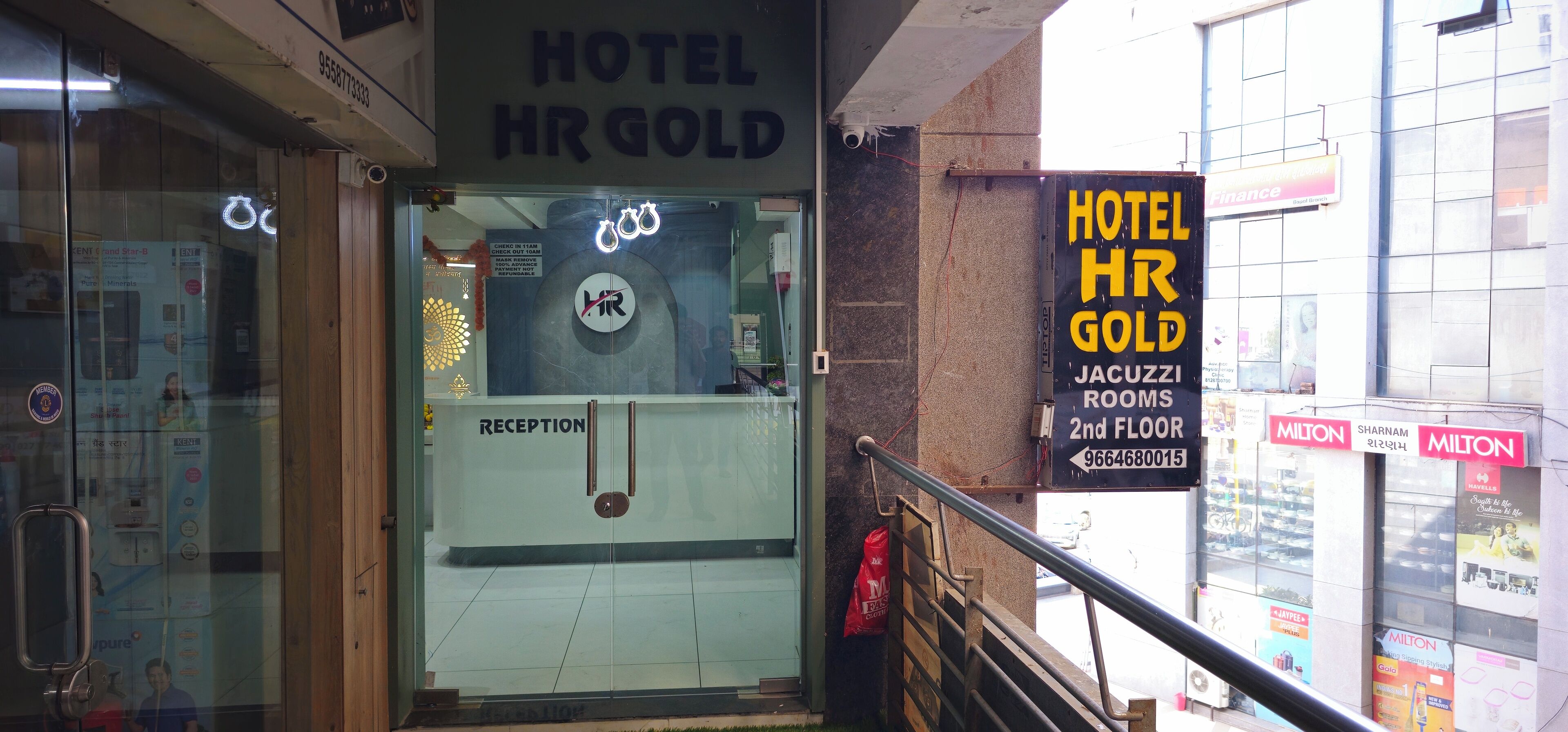 A hotel entrance with a reception desk, a sign for 'Hotel HR Gold' and 'JACUZZ ROOMS 2nd FLOOR,' and a visible fire extinguisher.