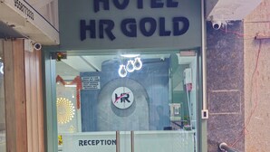 A hotel entrance with a reception desk, a glass door, and a sign reading 'HOTEL HR GOLD'. - Hotel HR Gold (Ahmedabad)
