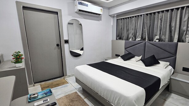 A modern bedroom with a bed, a mirror, a door, and an air conditioning unit. - Hotel HR Gold (Ahmedabad)