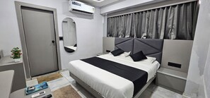 Une chambre moderne avec un lit, un miroir, une porte et un appareil de climatisation.