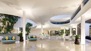 Eine geräumige Lobby mit hoher Decke, modernen Möbeln und Topfpflanzen.
