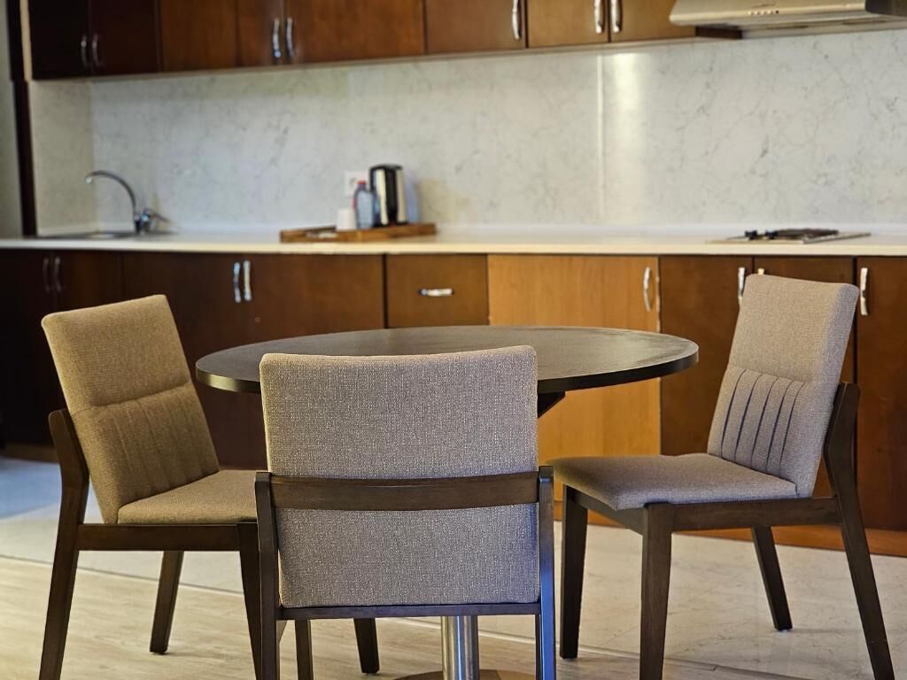 A modern kitchen with dark wooden cabinets, a round table, and two upholstered chairs.