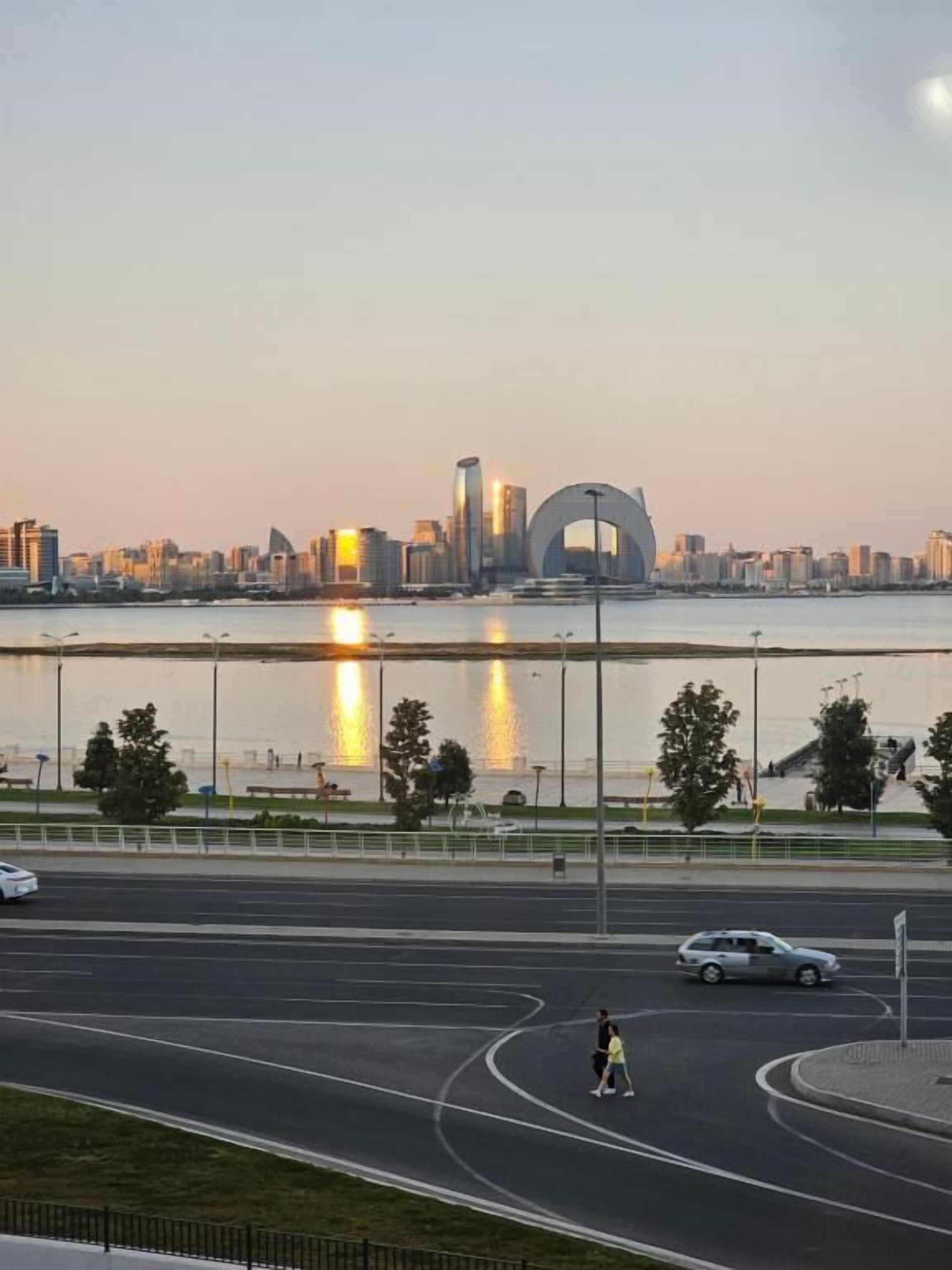 Paisagem urbana com uma ponte destacada e edifícios refletidos na água ao pôr do sol.