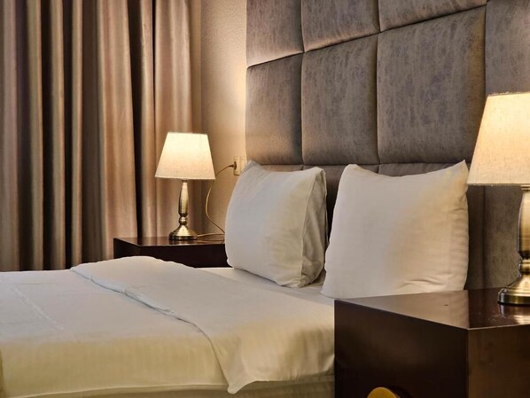 A hotel room with a bed, two bedside lamps, and a headboard. - CROWN APARTMENTS (Baku)
