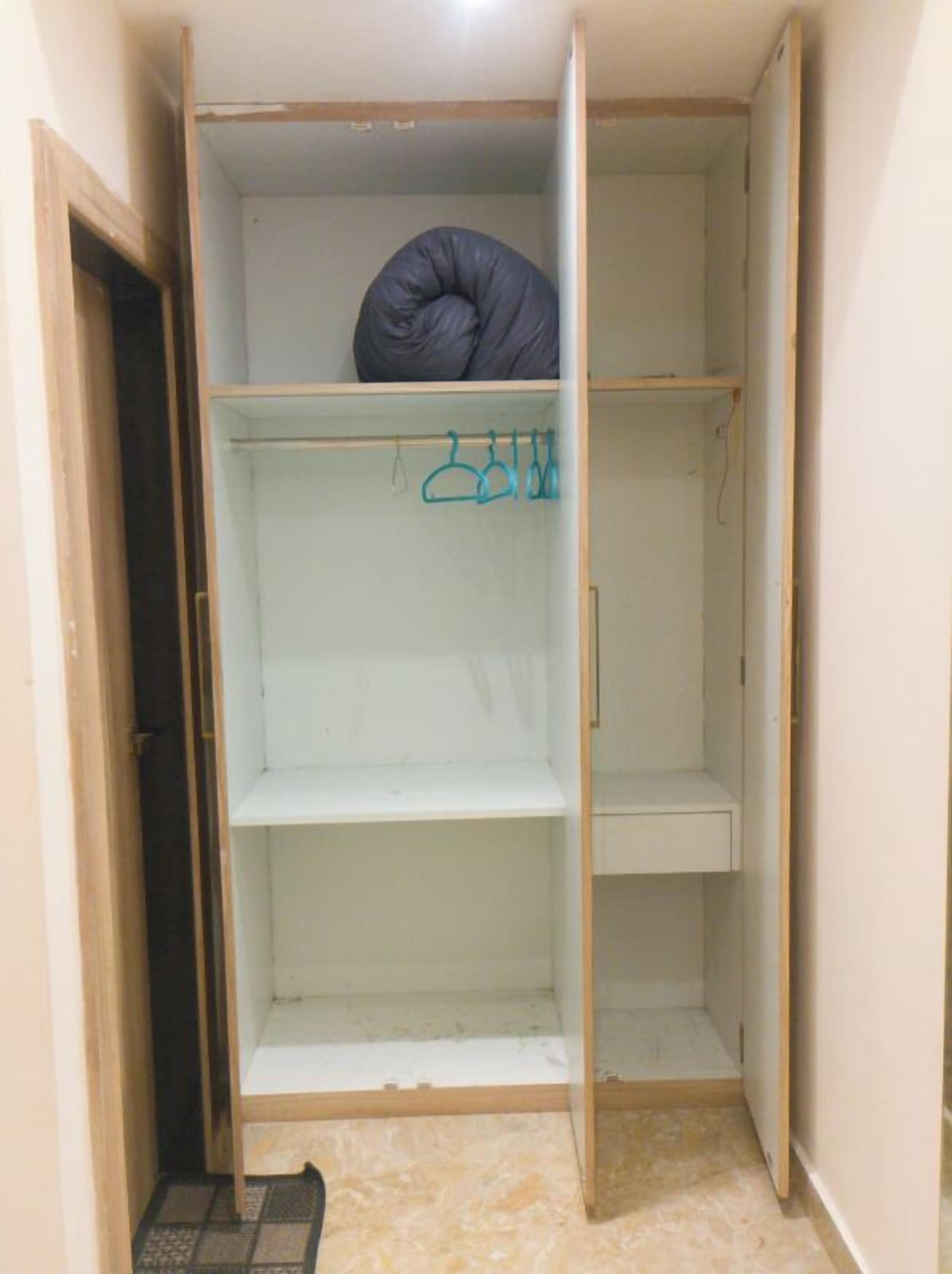 En walk-in-garderob med öppna dörrar, en klädstång och ett hoprullat föremål på den övre hyllan.