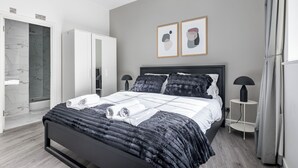 A modern bedroom with a bed, a wardrobe, a bedside table, and a shower area. - Luxury 2 Bedroom Apartment near London Bridge • Sleeps 6 • Tube Across Street (London)