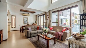 A spacious living room with a sofa, coffee table, and a view of a water body. - Staymaster Aqua Cottage 3BR Villa  (Vagator)