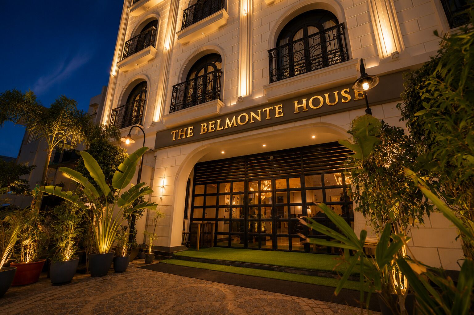 A building with a sign reading 'THE BELMONTE HOUSE' at night.