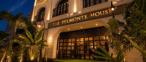 A building with a sign reading 'THE BELMONTE HOUSE' at night.