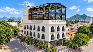 A luxury boutique hotel with a bar and lounge on the upper floor, surrounded by lush greenery and mountains in the background. - Belmonte House, Udaipur (Udaipur)