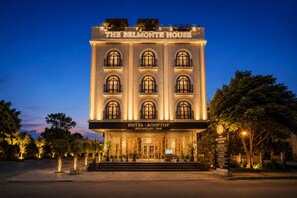 Un hôtel doté d’un restaurant et d’un bar situés sur le toit, appelé « The Belmonte House », qui présente un style architectural classique avec des fenêtres en arc et une façade bien éclairée.