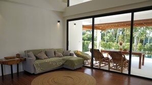 A modern living room with a sofa, a round woven rug, and wicker chairs. - O3 Green 2b Garden Pool Villa and Unique Furniture (Ko Pha-ngan)