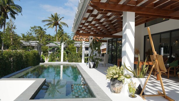 A modern pool area with a wooden pergola, potted plants, and an easel. - O3 Green 2b Garden Pool Villa and Unique Furniture (Ko Pha-ngan)