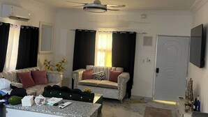 A living room with a sofa, a coffee table, a TV, and a ceiling fan.