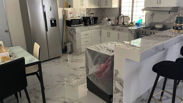 A modern kitchen with marble flooring, stainless steel appliances, and white cabinetry.