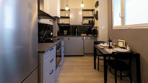 A compact kitchen with a built-in oven, a dining table with chairs, and pendant lighting. - Quiet apartment 6 min walk to metro - 4 stops to Opera (Wien city)