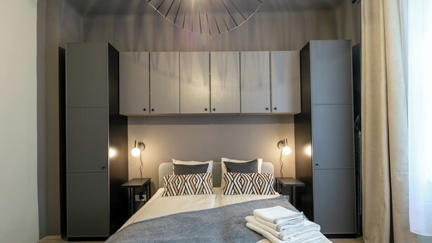 A modern bedroom with a bed, bedside tables, a wardrobe, and a hanging light fixture. - Quiet apartment 6 min walk to metro - 4 stops to Opera (Wien city)