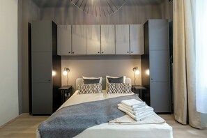 Une chambre moderne avec un lit, des tables de chevet, une armoire et un luminaire suspendu.