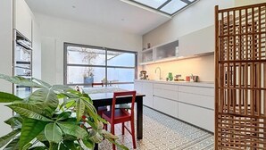 A modern kitchen with a skylight, a dining area with a table and chairs, and a patterned floor. - Anavel Atao (Lille)