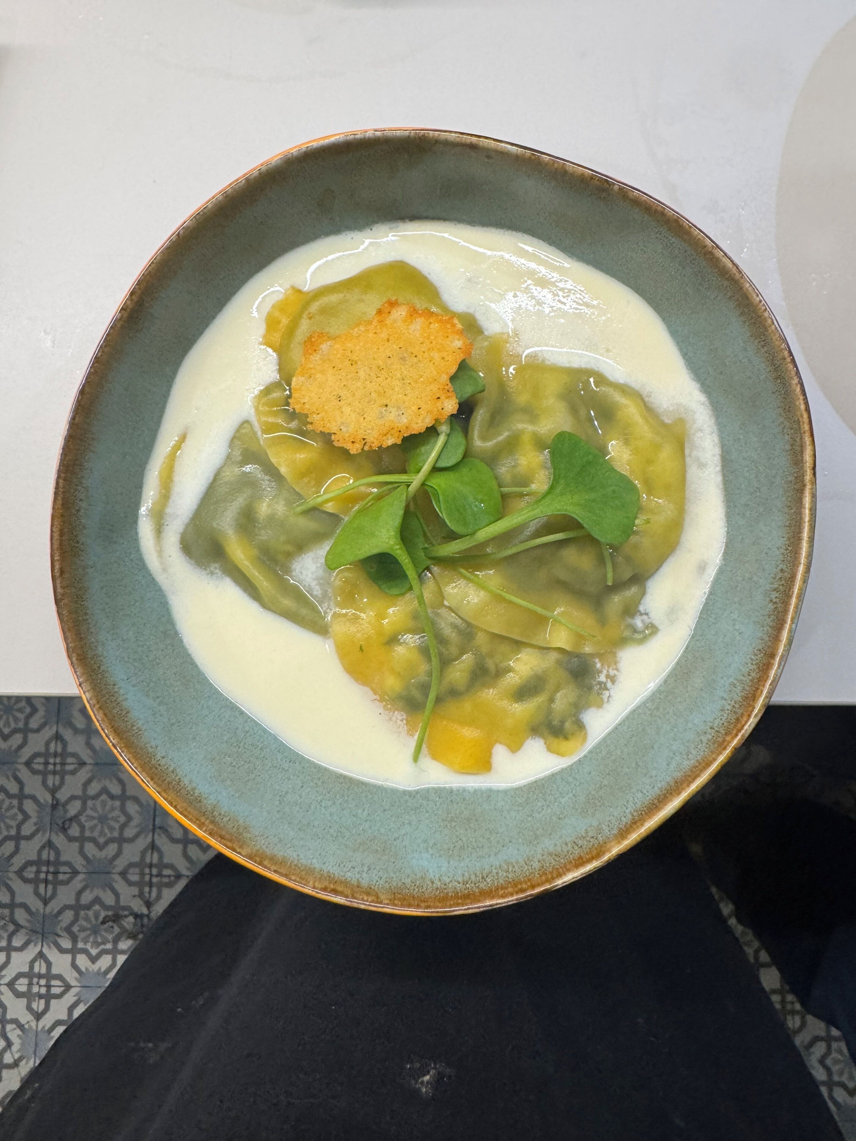 Un bol d'aliments amb una base cremosa de sopa, verdures verdes i un cruixent daurat.