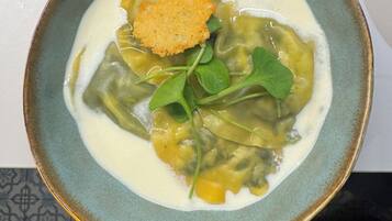 Un bol d'aliments amb una base cremosa de sopa, verdures verdes i un cruixent daurat.