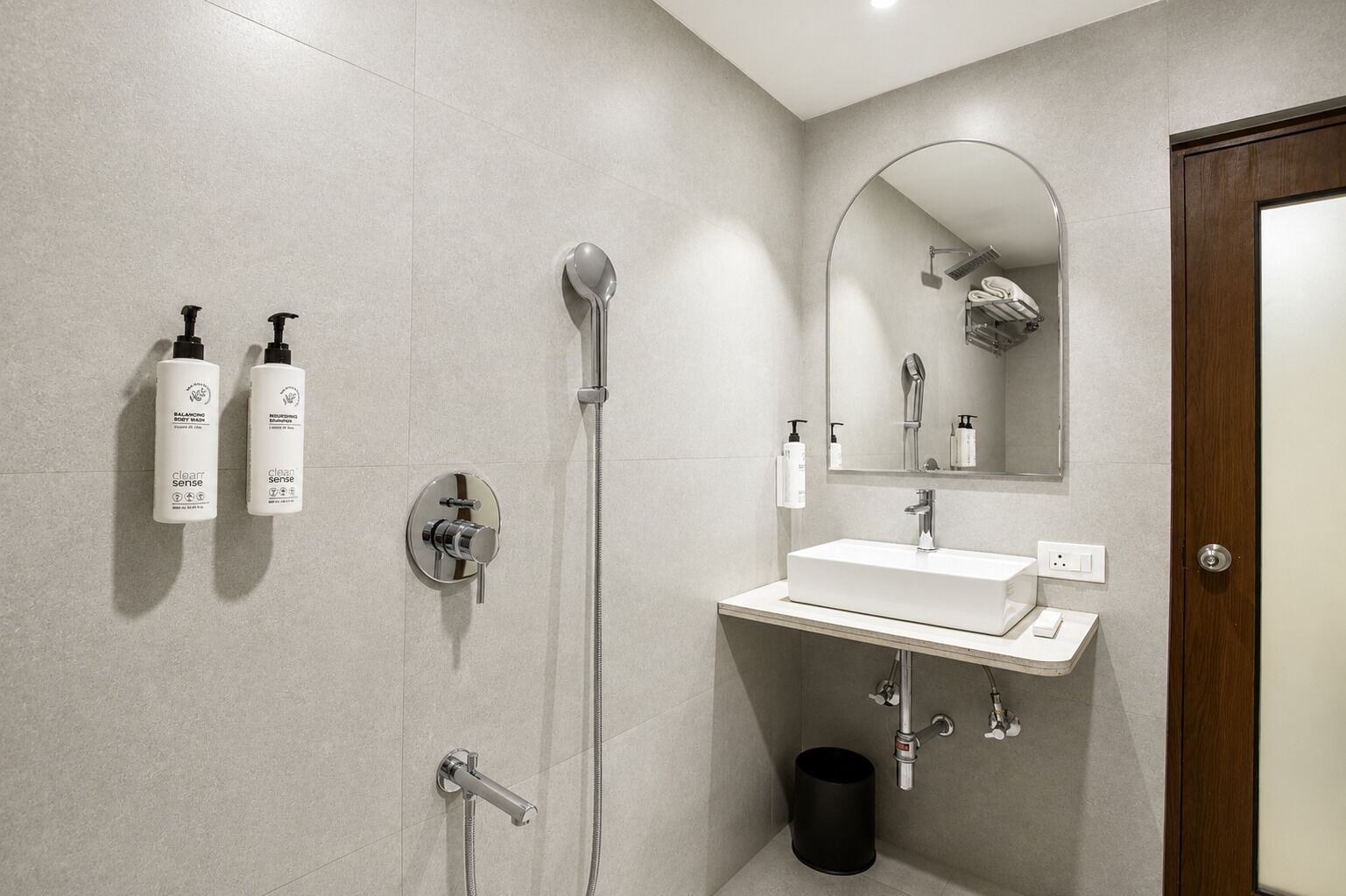 A modern bathroom with a shower, a sink, and a mirror.