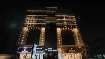 Un hotel de varios pisos con señalización iluminada, incluyendo 'Hotel Eagle Empire' y 'Caratlane'.