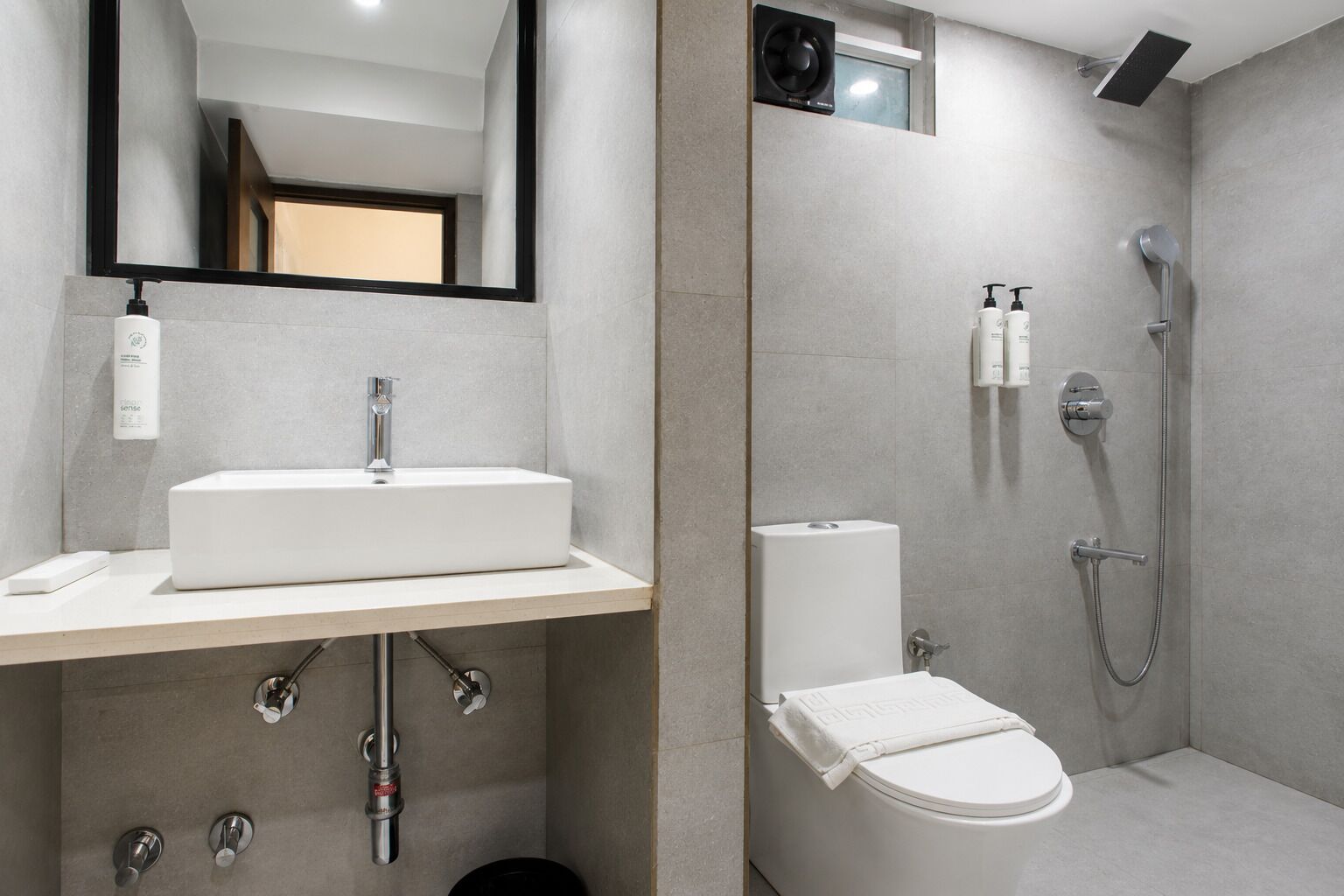Un baño moderno con un lavamanos rectangular, un inodoro, una ducha y un espejo.
