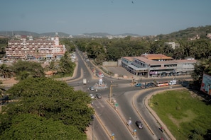 A multi-story building with a commercial ground floor, a curved road with vehicles, and surrounding greenery.