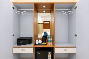 Habitación de hotel con minibar, cafetera, botellas de agua y refrigerador.