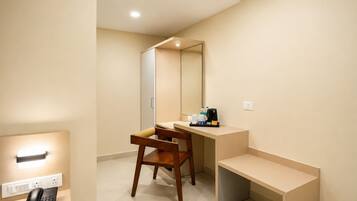 A hotel room with a wooden desk, a mirror, a telephone, and a coffee maker on the counter.