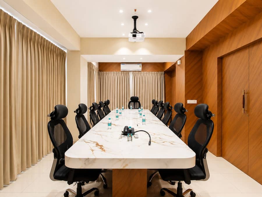 A conference room with a long table, multiple chairs, and a projector.