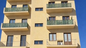 Un edificio de varios pisos con balcones, ventanas amplias y puertas de garaje.