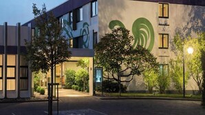 Un bâtiment moderne, doté d’un grand logo vert, d’une entrée abritée et d’une rue bien éclairée.